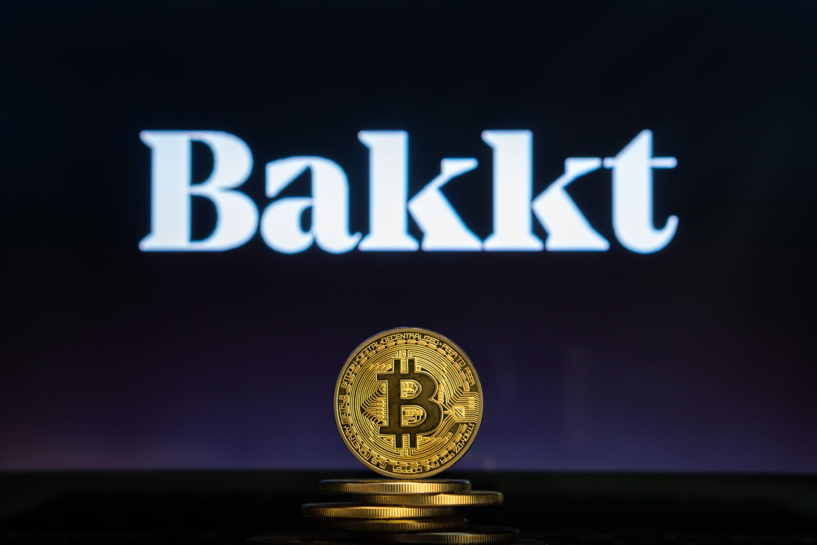 The Bakkt logo behind a Bitcoin by 24K-Production via Shutterstock
