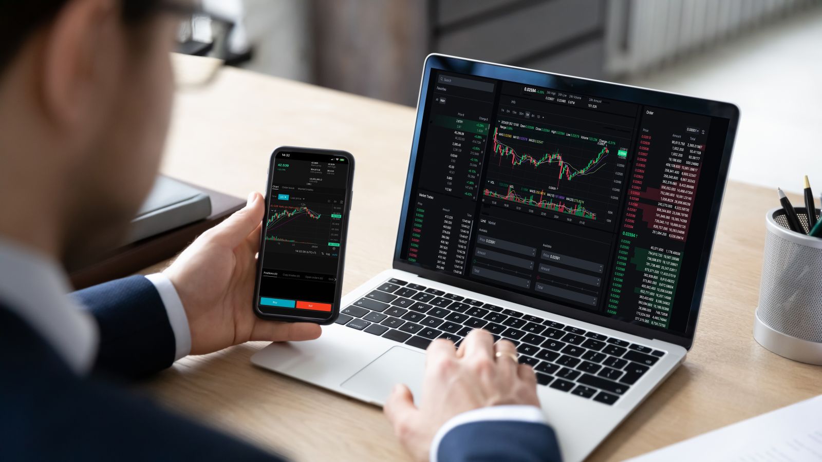 Trader on laptop and smart phone by fizkes via Shutterstock
