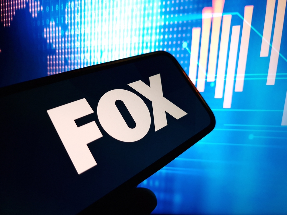 Communication Services - Fox Corporation phone with blue background by-Piotr Swat via Shutterstock