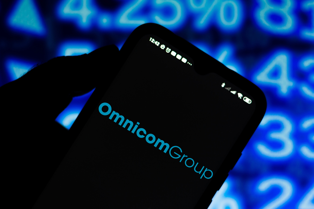 Communication Services - Omnicom Group, Inc_ phone with blue background by- rafapress via Shutterstock
