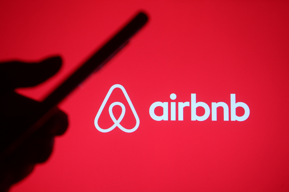 Airbnb Inc logo with red background by- viewimage via Shutterstock