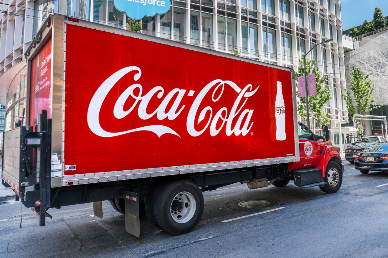 Consumer Defensive - Coca-Cola Co logo on trailer by- Sundry Photography via iStock