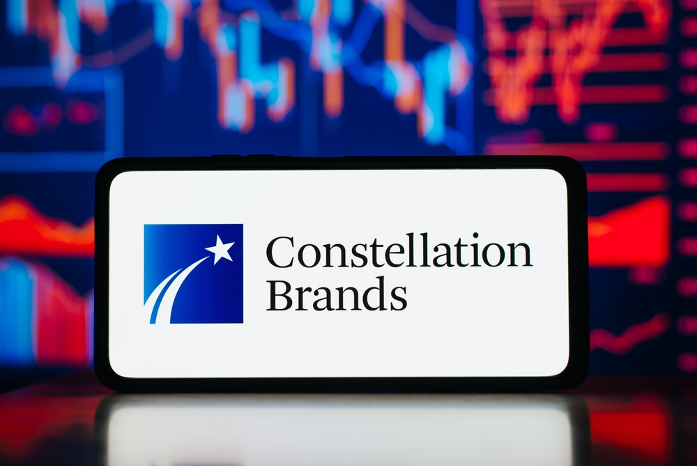 Consumer Defensive - Constellation Brands Inc logo on phone with data -by Sergio Photone via Shutterstock