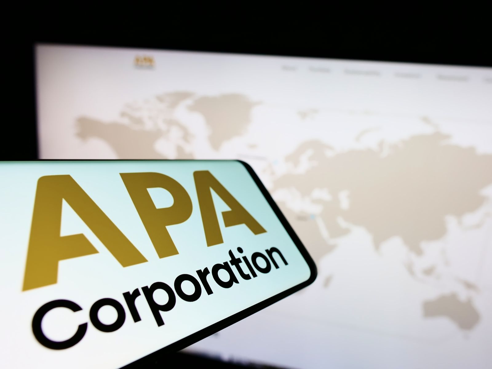 Smartphone with logo of American petroleum company APA Corporation on screen in front of business website by Timon