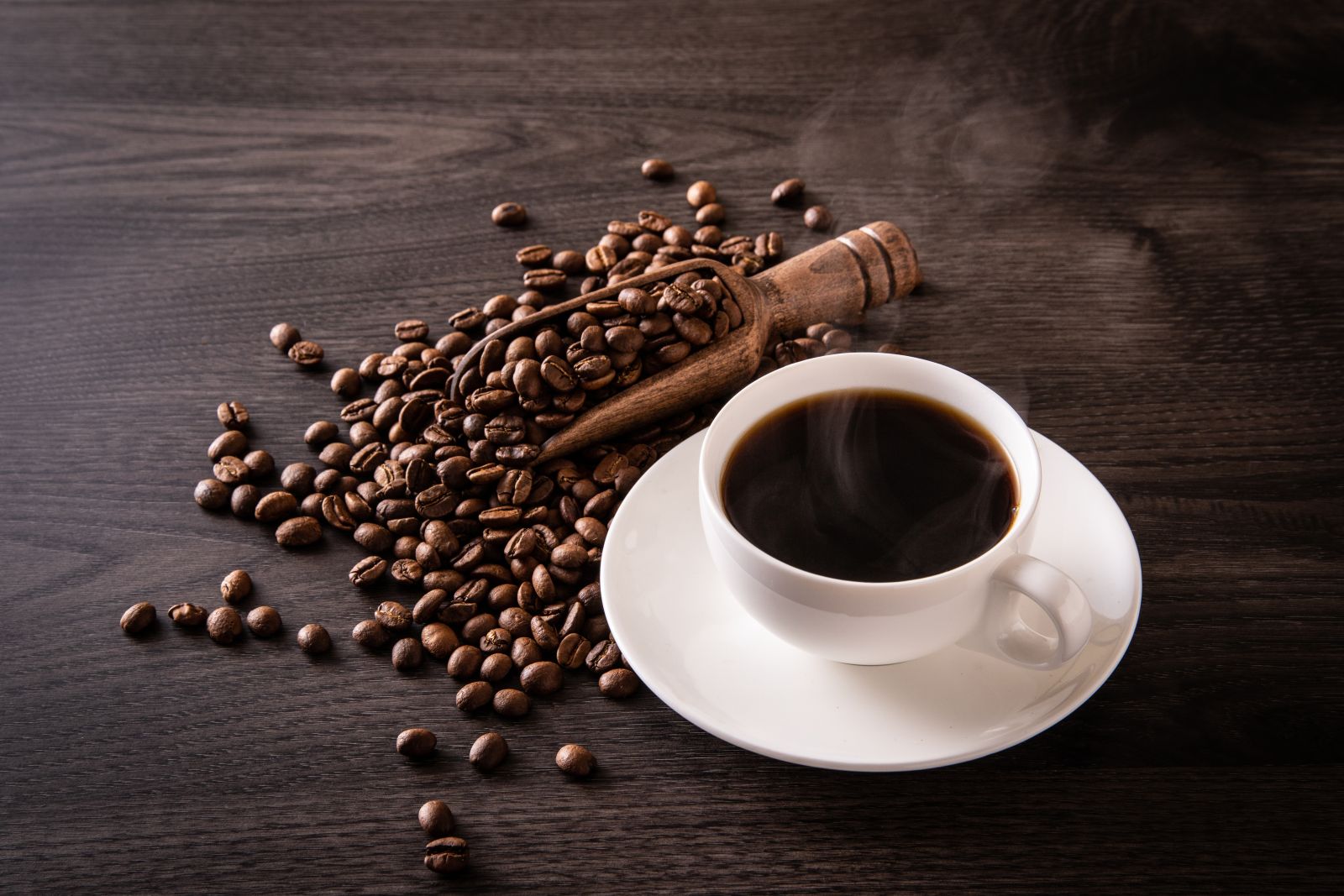 Coffee beans and hot coffee on the table by Jazz3311 via Shutterstock