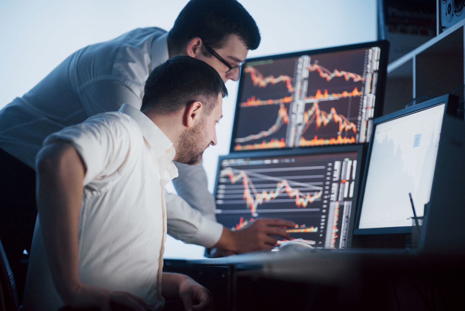 Charts, tickers, traders - Stock brokers analyzing stocks on screen by Standret via Shutterstock