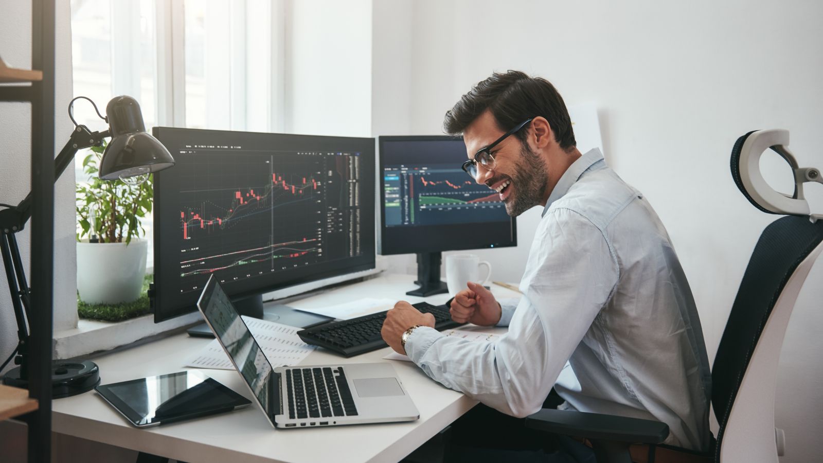 Charts, tickers, traders - Trader happy with results by Dima_Sidelnikov via iStock