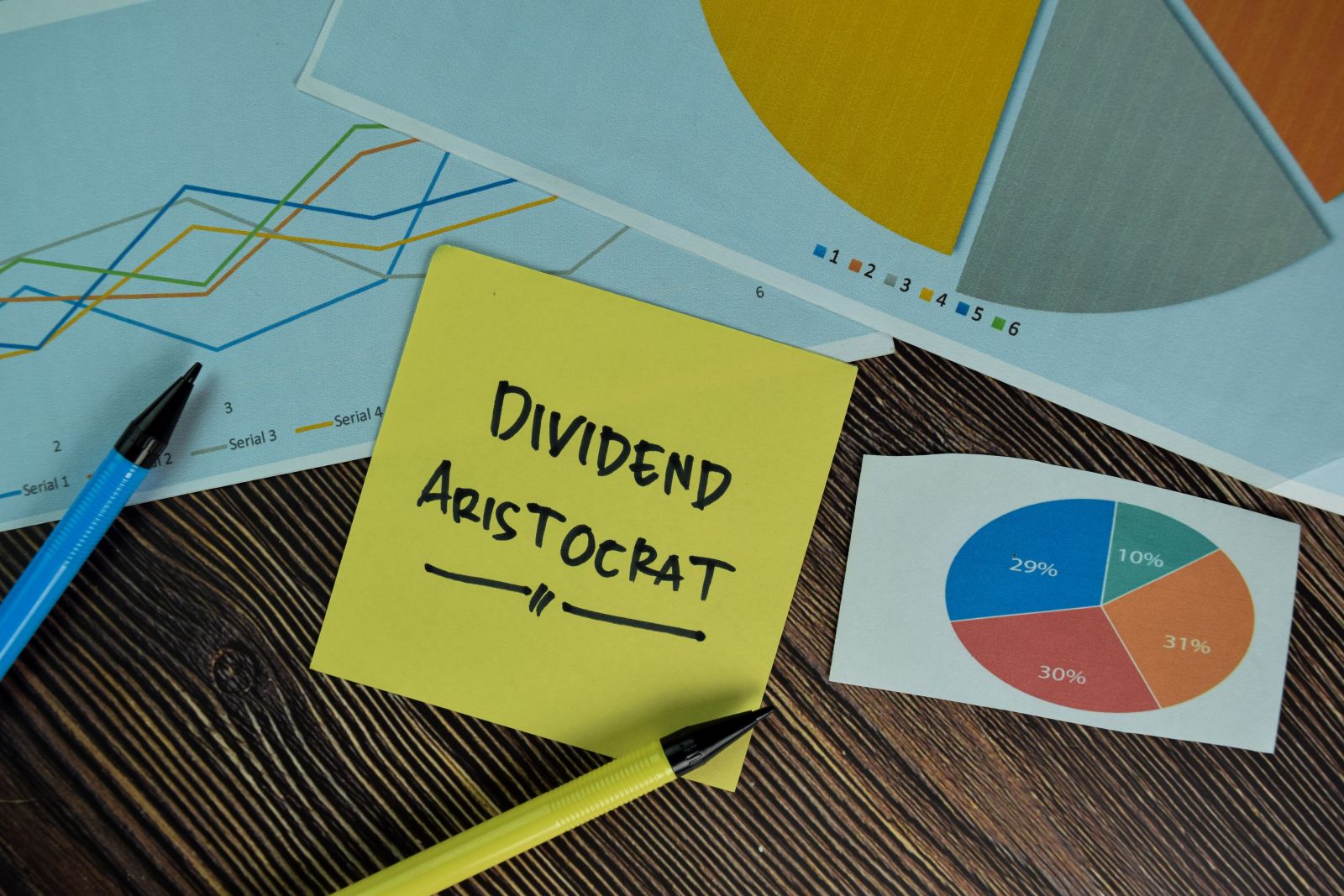 Dividends - Dividend Aristocrat write on sticky notes isolated on Wooden Table by Bangoland via Shutterstock