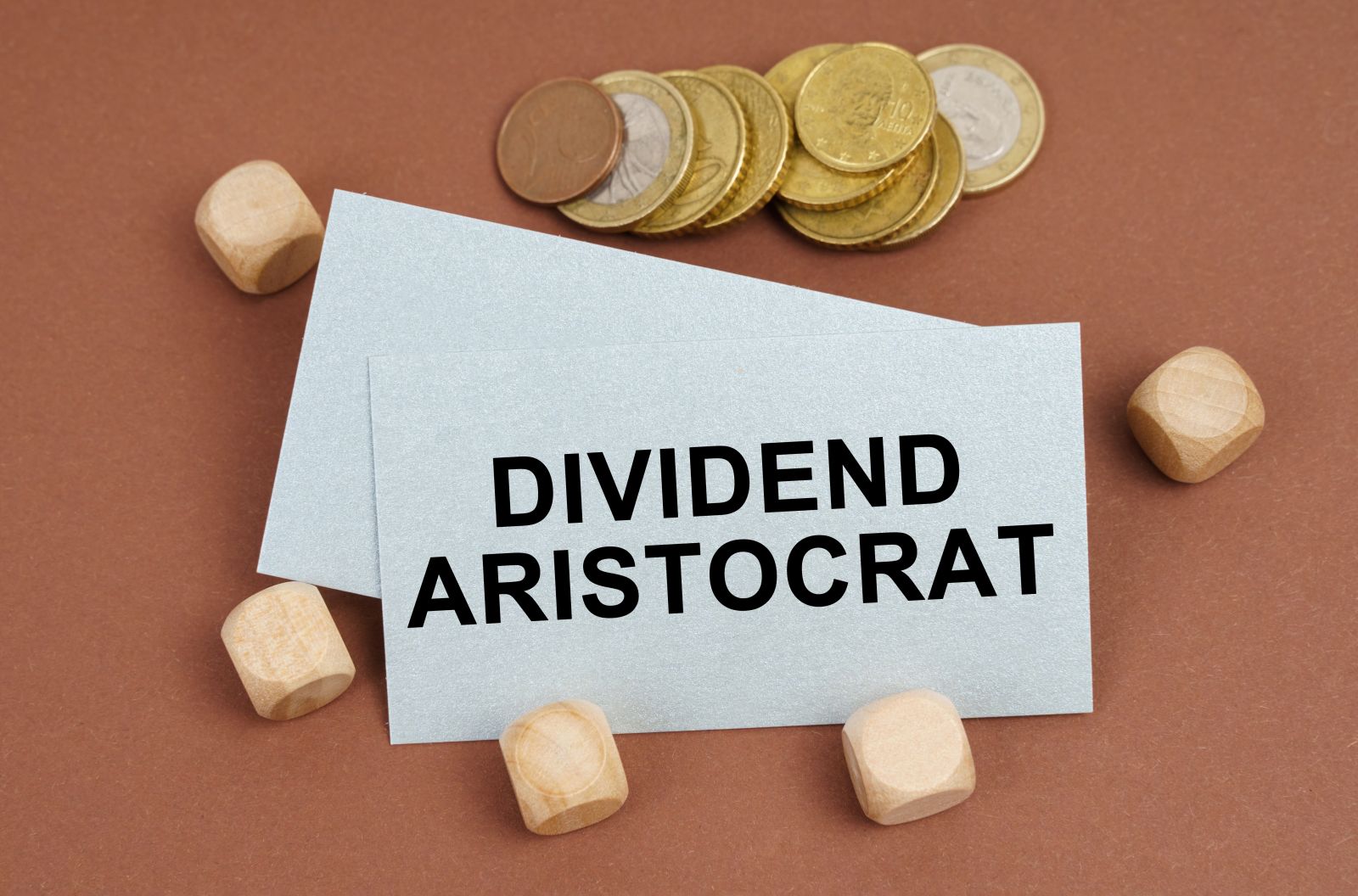 coins, cubes and a business card with the inscription - Dividend Aristocrat by SkazovD via Shutterstock