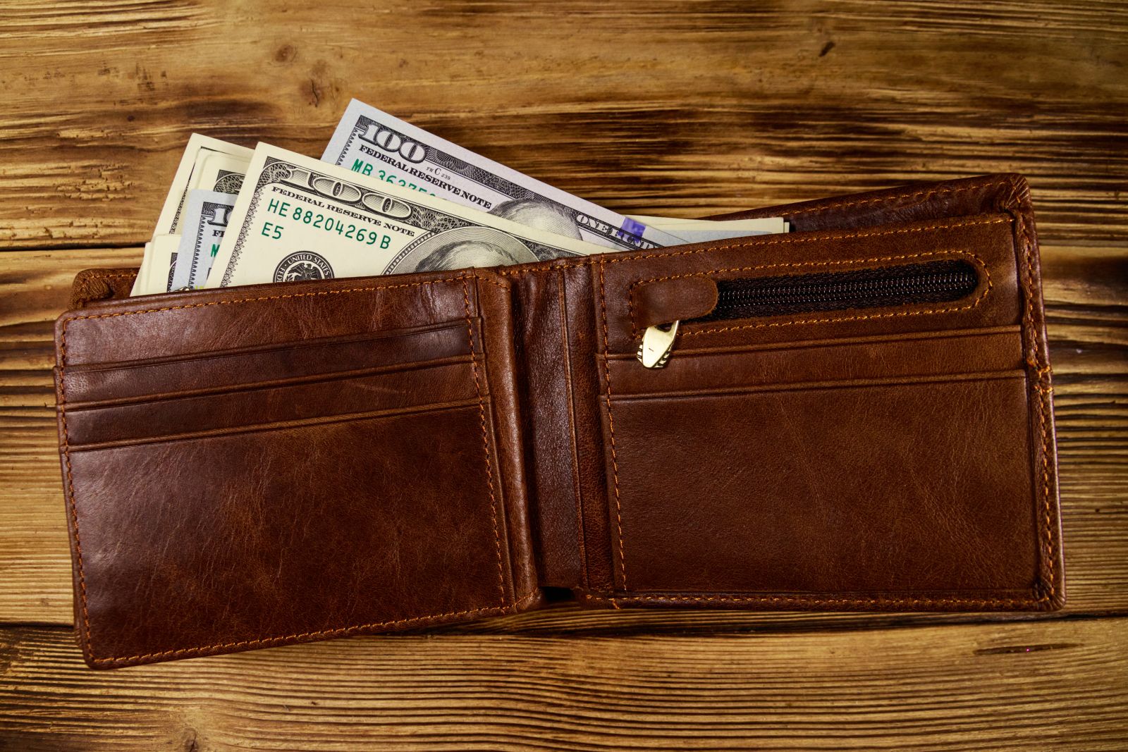 Opened wallet with US dollars on table by olyasolod via Adobe Stock