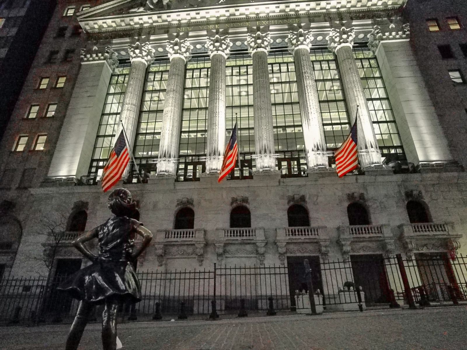 Fearless Girl looking up at Wall Street at Night by Tim Pruss via iStock