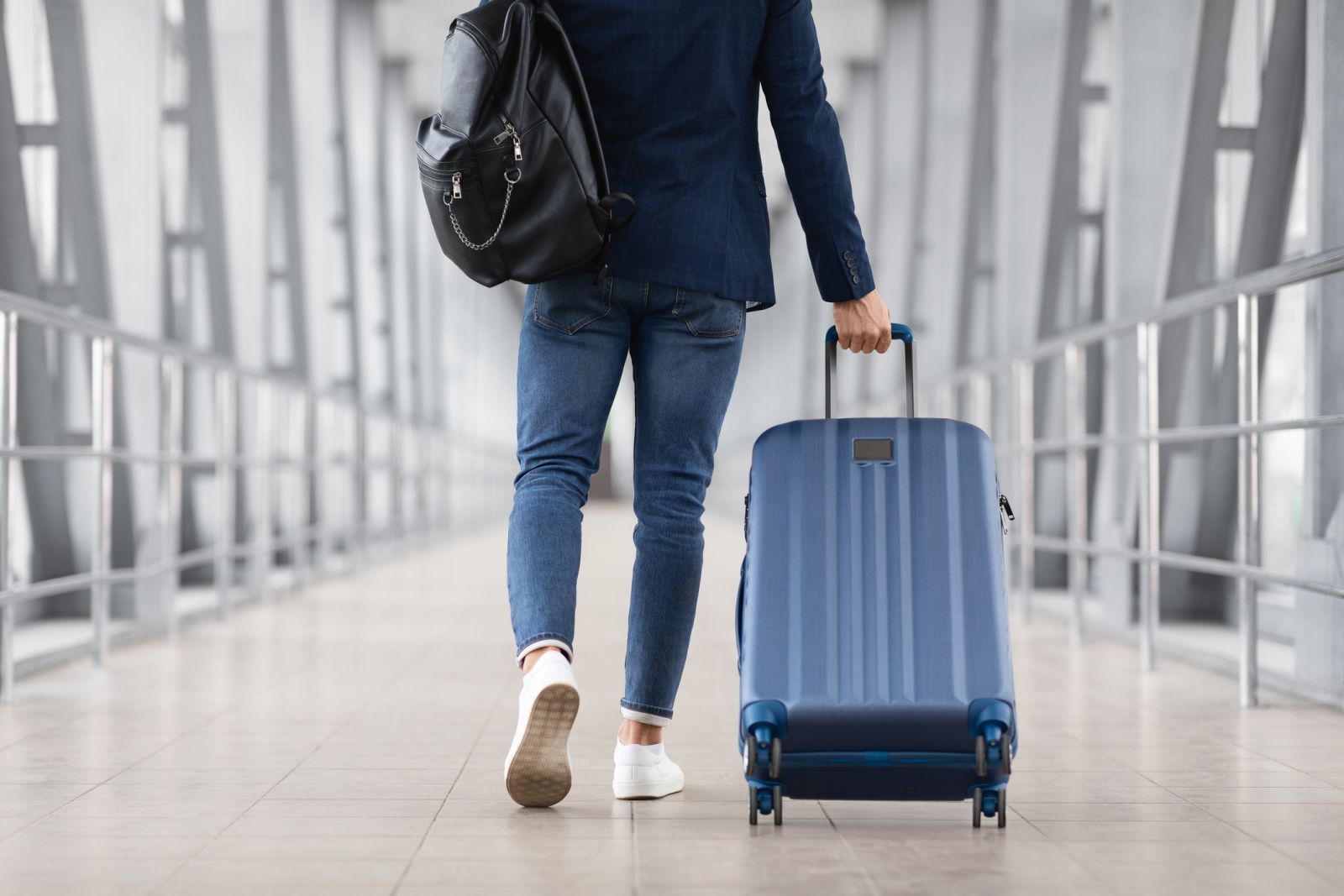 Man walking thorugh airport with luggage by Prostock-Studio via iStock