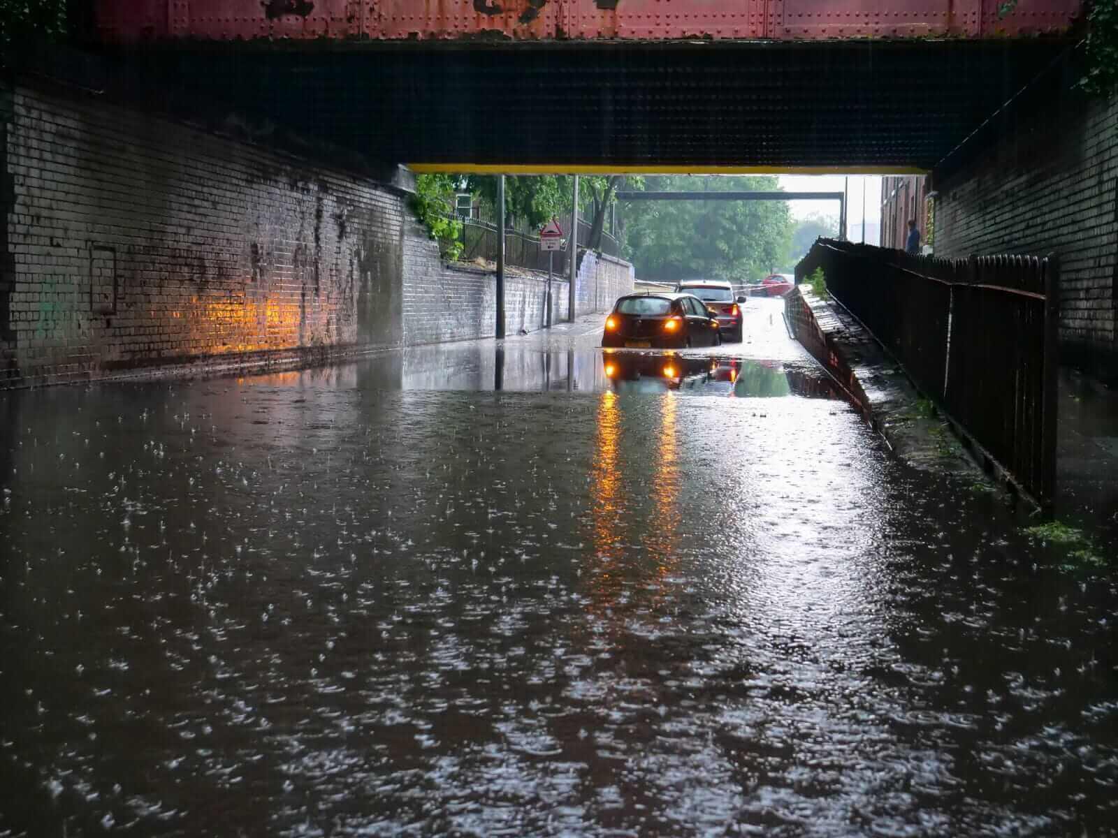 Two cars stranded in flood water under low bridge by opal2 via Istock