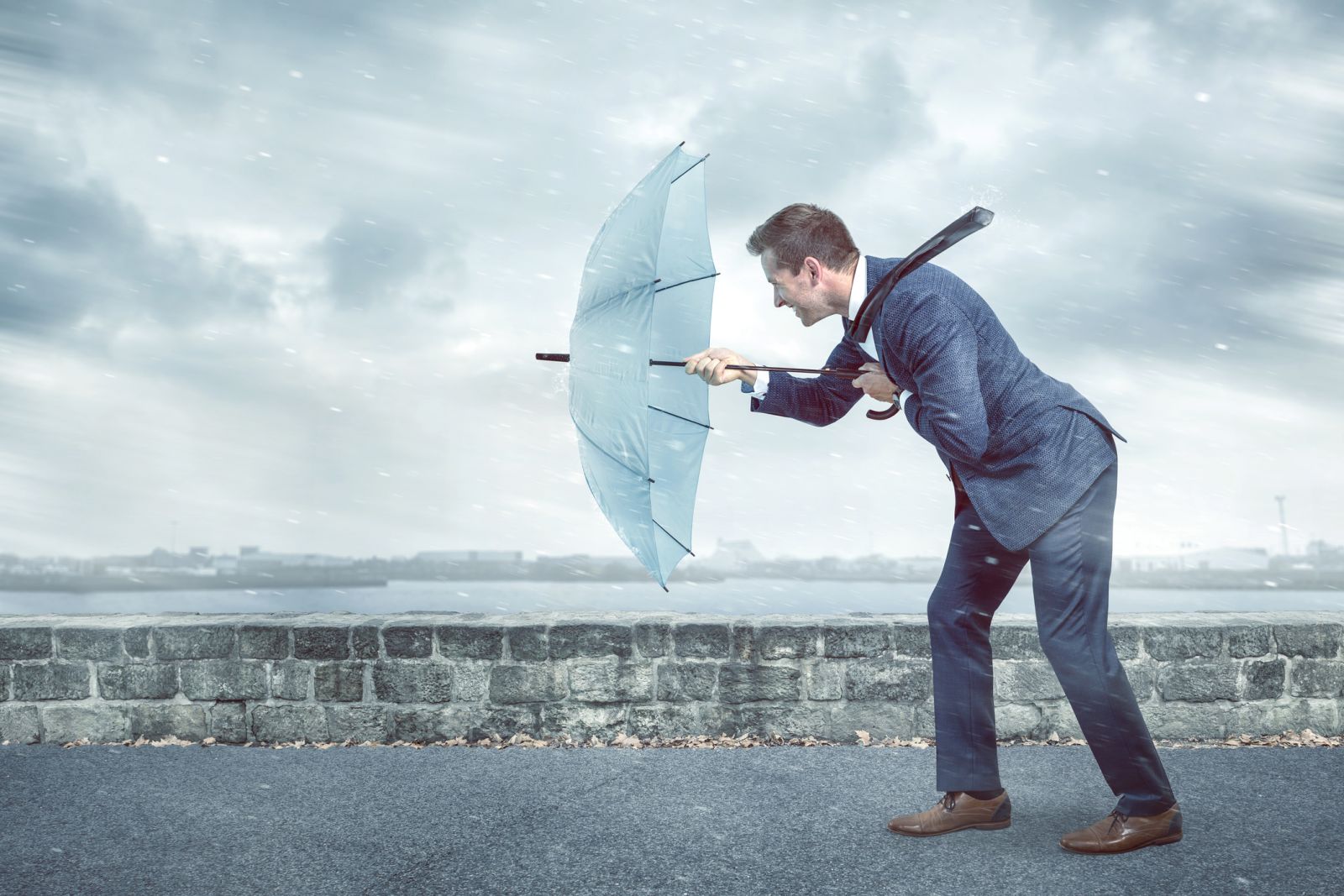 businessman with umbrella against thunderstorm overcoming challenge by photoschmidt via iStock